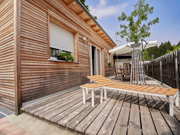 Casa in legno con terrazza e sedia a sdraio.