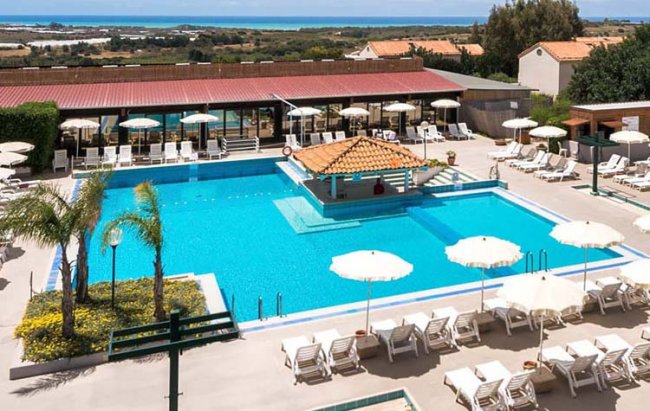 Piscina con lettini e ombrelloni bianchi.