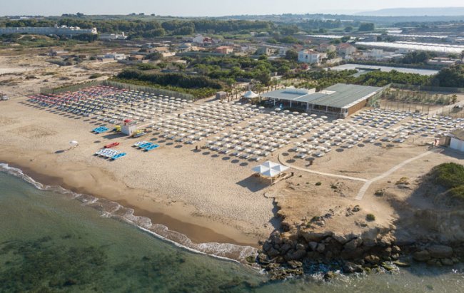 Spiaggia attrezzata con ombrelloni e lettini, vista dall'alto.