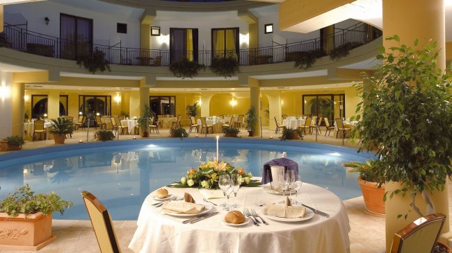 Tavolo apparecchiato a bordo piscina in un hotel elegante.