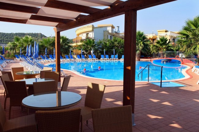 Ampia piscina all'aperto con sedie e ombrelloni blu.