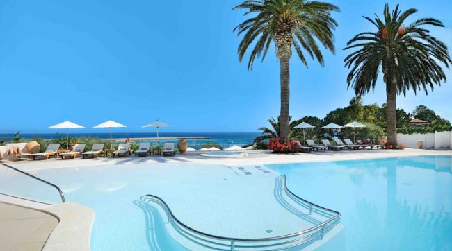 Piscina all'aperto con palme vista mare.