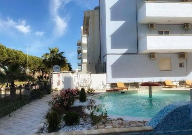 Piscina circondata da palme e edificio bianco.