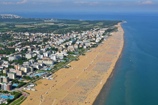 Spiaggia affollata con edifici costieri.