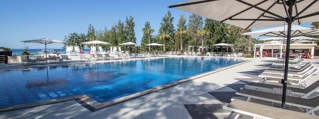Piscina grande circondata da lettini e ombrelloni.