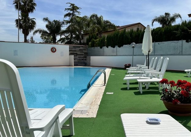 Piscina esterna con sdraio bianche.