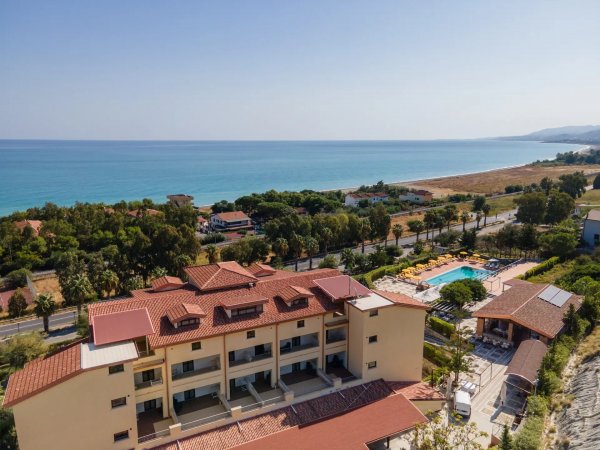 Veduta aerea di un edificio con piscina e vista sul mare.