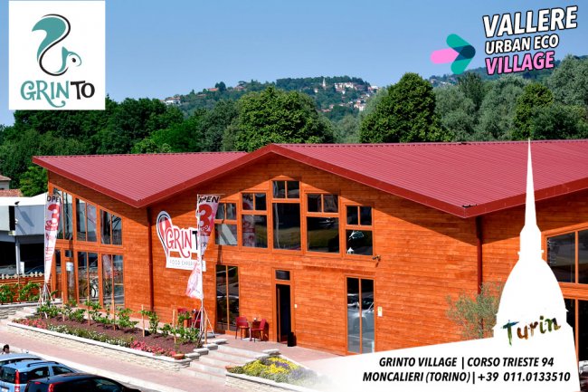 Edificio in legno con tetto rosso, vegetazione sullo sfondo.