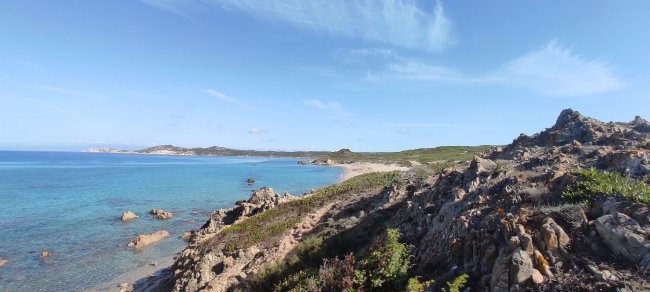 Costa rocciosa con mare blu e cielo limpido.