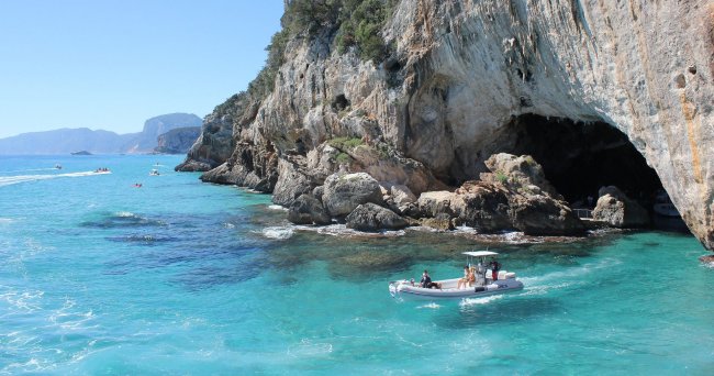 Barca a motore vicino a una grotta sulla costa.