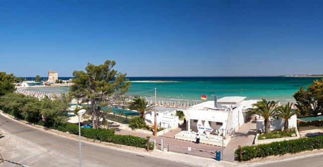 Spiaggia con mare blu e costruzioni costiere.