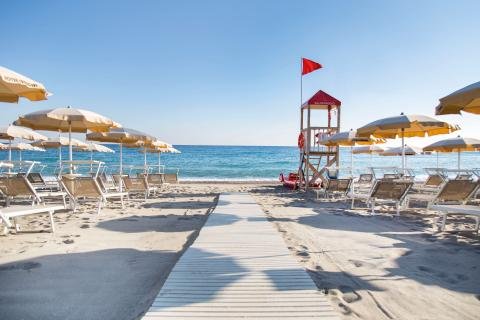 Spiaggia con sdraio e ombrelloni gialli.