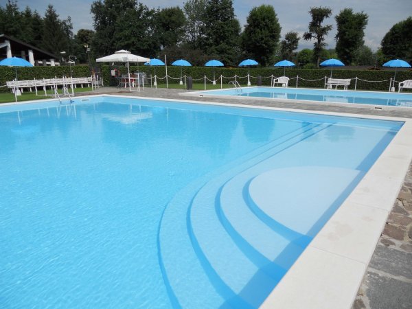 Piscina all'aperto con ombrelloni blu.