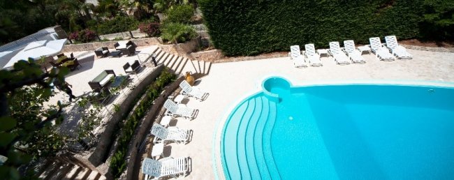 Piscina all'aperto con lettini bianchi.