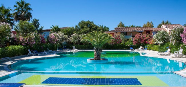 Piscina circondata da vegetazione e lettini.