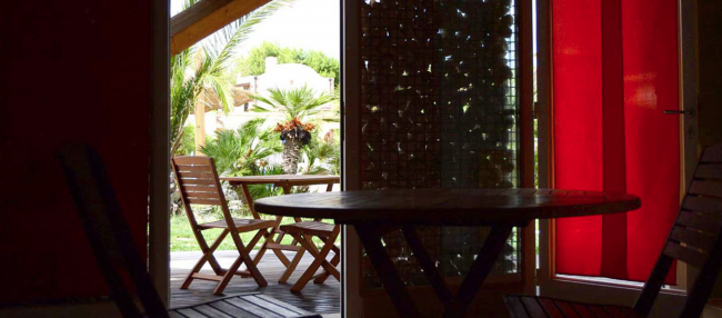 Interno con tavolo e sedie, vista su giardino.