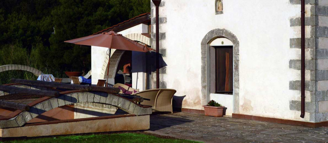 Edificio in pietra con patio e ombrellone.
