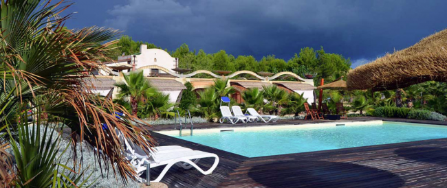 Piscina con lettini e giardino tropicale.