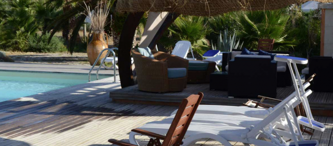 Lettini e poltrone su una terrazza in legno.