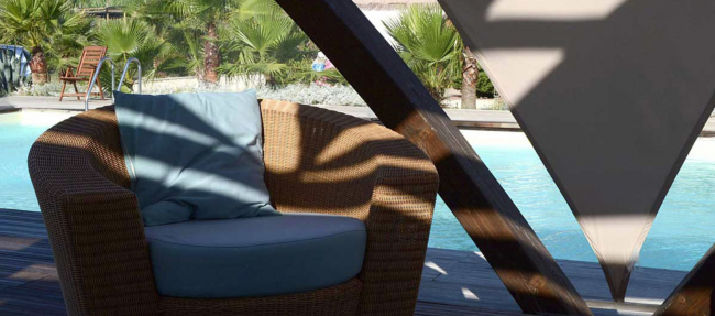 Sedia in vimini accanto a una piscina soleggiata.