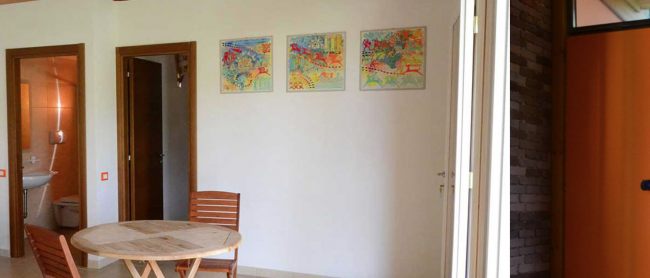 Sala con tavolo e sedie, porta verso il bagno.