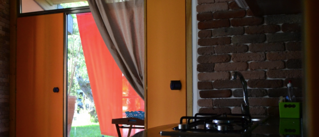 Cucina con mattoni e tende rosse.