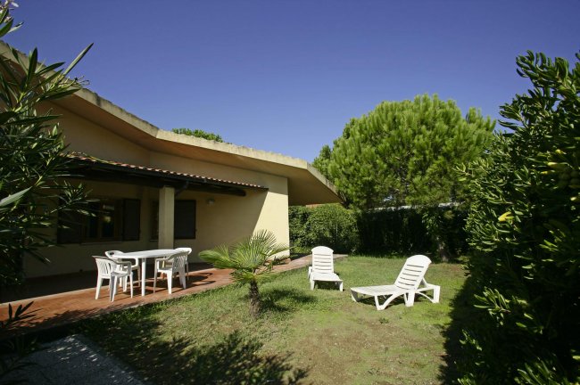 Giardino con sdraio e tavolo sotto un cielo limpido.