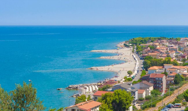 Spiaggia con mare blu e case costiere.