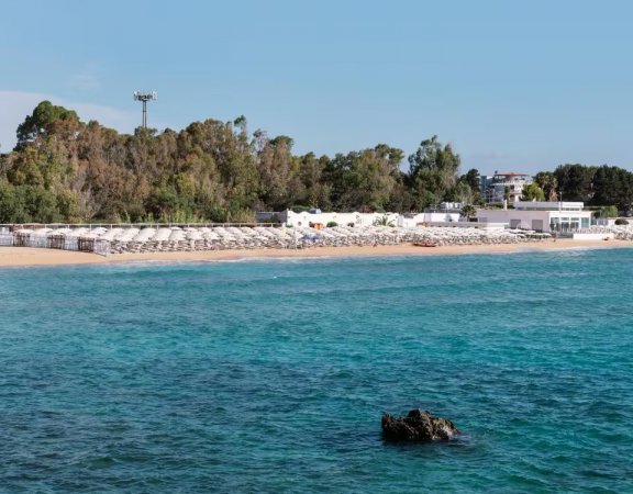 Spiaggia sabbiosa con ombrelloni e mare turchese.