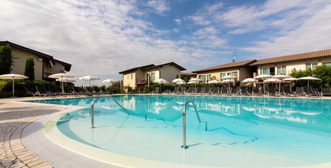 Piscina all'aperto con lettini e ombrelloni.
