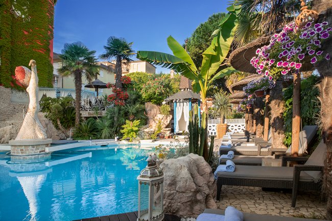 Piscina circondata da lettini e piante tropicali.