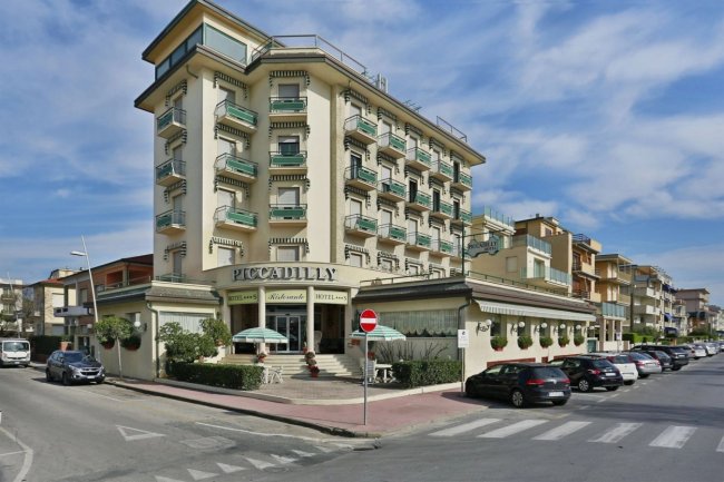 Hotel angolare su strada alberata, struttura di più piani.
