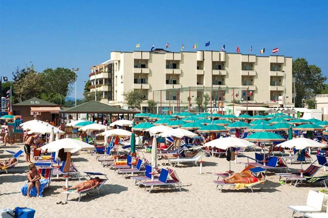 Spiaggia affollata con lettini e ombrelloni.