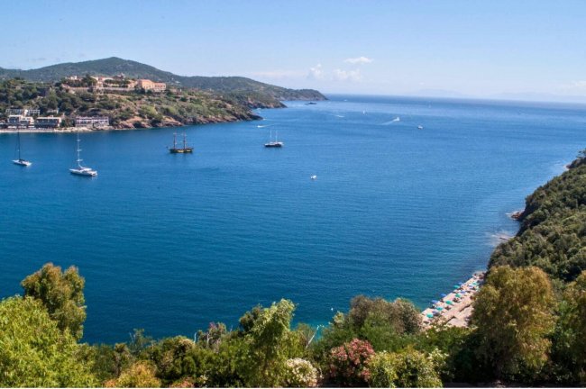 Vista panoramica su baia con barche e costa verde.