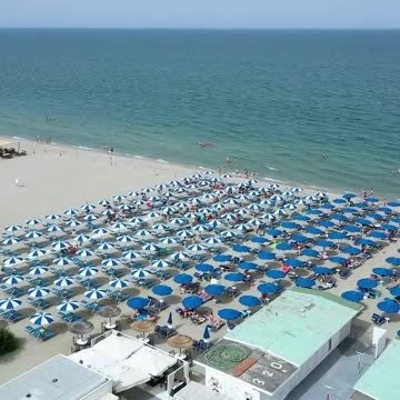 Vista aerea di ombrelloni blu sulla spiaggia.