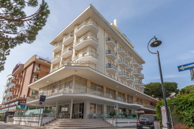 Edificio angolare con balconi e alberi.