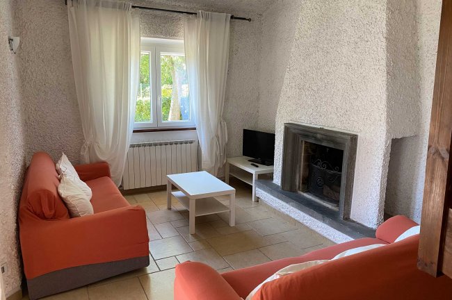 Soggiorno con divani arancioni e camino.