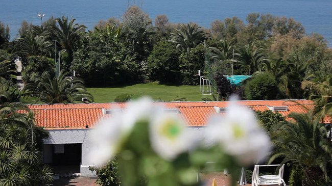 Giardino e tetti con mare sullo sfondo.