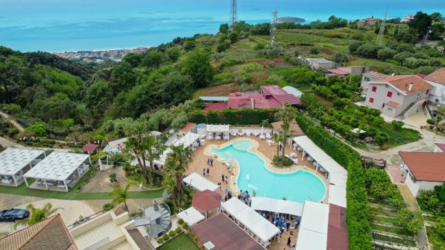 Piscina e verde collinare vicino al mare.
