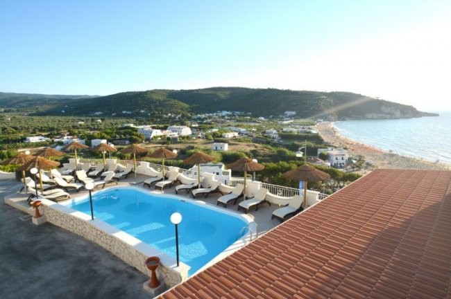 Piscina con lettini e paesaggio collinare.