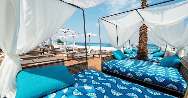 Letti a baldacchino con cuscini blu vicino al mare.