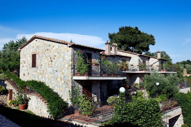 Edificio in pietra con balconi e piante rampicanti.
