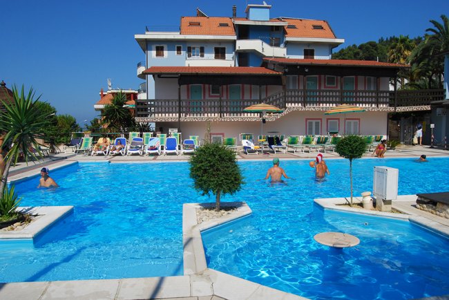 Piscina all'aperto con persone e sedie a sdraio.