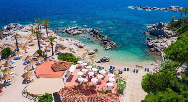 Spiaggia con sdraio e ombrelloni, mare blu.