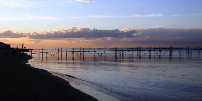 Spiaggia con mare calmo al tramonto.