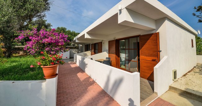 Bungalow bianco con giardino e fiori colorati.