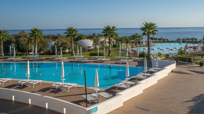 Piscina con lettini e vista sul mare.
