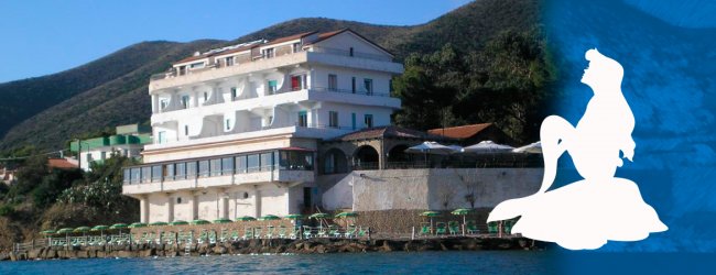 Edificio sul mare con ombrelloni verdi.
