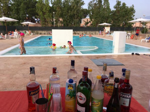 Piscina con bambini e tavolo con bottiglie.