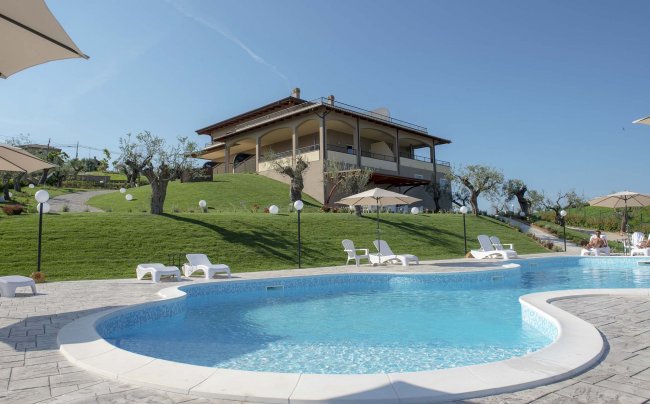 Una piscina con sedie a sdraio e una villa sullo sfondo.